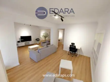 Contemporary living room with gray sofas, a television, and a desk chair in a well-lit space.