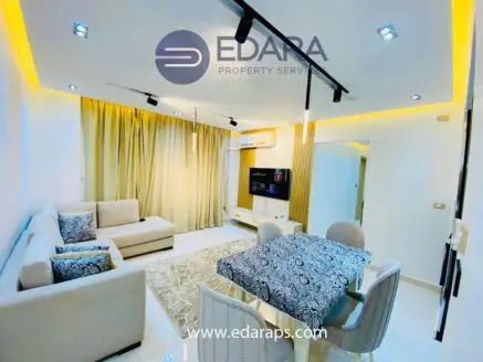Contemporary living room featuring a sofa, dining table, and decorative lighting.
