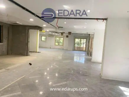 Interior view of a renovated space with polished floors and unfinished walls, showcasing an open layout.