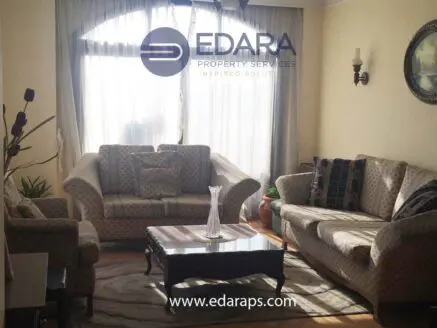 Living room featuring two patterned sofas, a coffee table, and a decorative vase on the table.