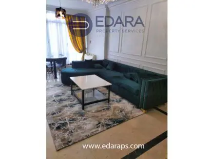 Contemporary living room featuring a green sectional sofa and a white coffee table on a patterned rug.