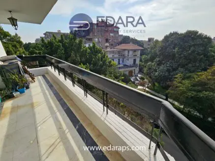 Balcony with a railing overlooking a residential area in Cairo with trees and buildings.