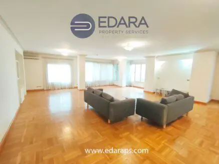 Bright and spacious living room featuring two gray sofas and wooden flooring.