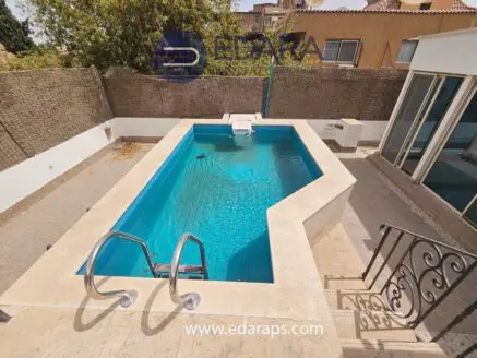 Rectangular swimming pool with clear blue water and steps leading in, surrounded by a stone deck.