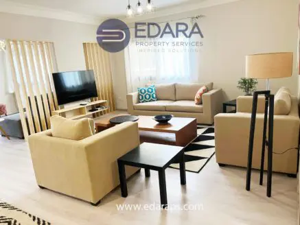Living room featuring beige sofas, a television, and a coffee table in a contemporary design.