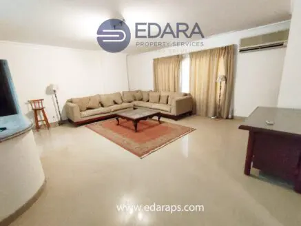 Spacious living room featuring a beige sectional sofa and a wooden coffee table on a rug.