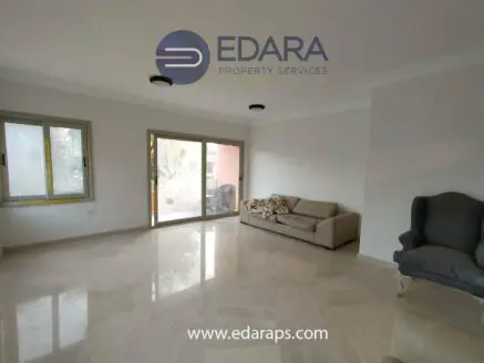 Bright living room featuring a beige sofa and a gray armchair on marble flooring.
