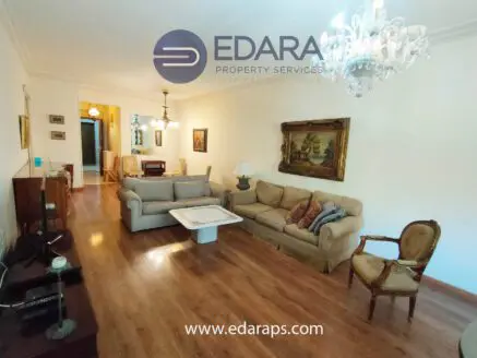 Spacious living room featuring a light-colored sofa, an armchair, and a chandelier overhead.
