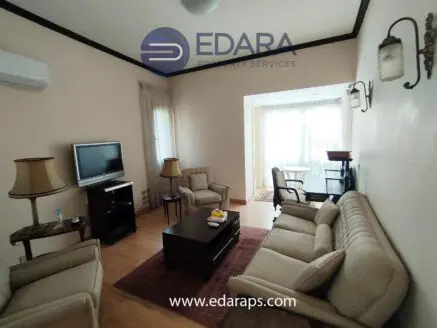 Living room featuring beige sofas, a television, and a coffee table in a well-lit space.