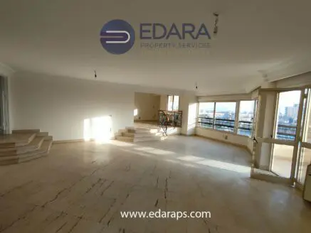 Bright and spacious unfurnished living room with large windows and marble flooring.