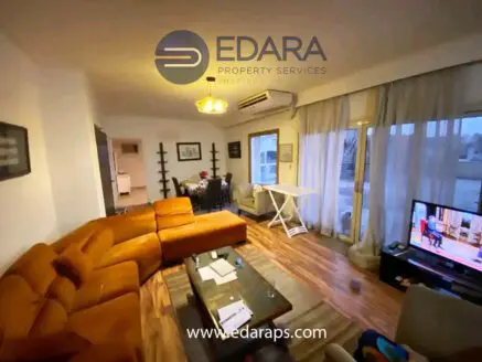 Interior view of a living room featuring an orange sectional sofa and a television set.