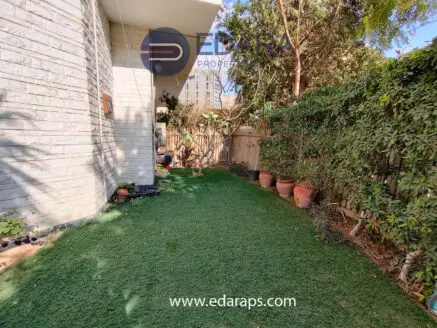 Lawn area with artificial grass and potted plants along a fence in a residential setting.