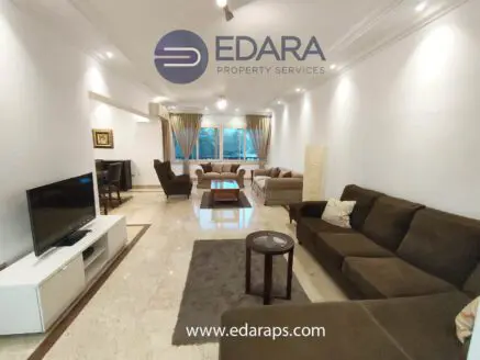 Spacious living room featuring brown sofas, a coffee table, and a television on a white cabinet.