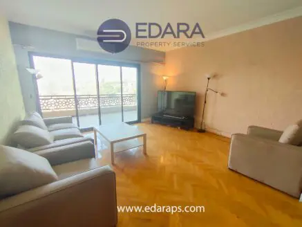 Spacious living room featuring two sofas, a coffee table, and a television with a balcony view.