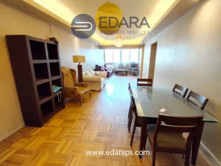 Interior view of a living space featuring a dining table and seating area with natural light.