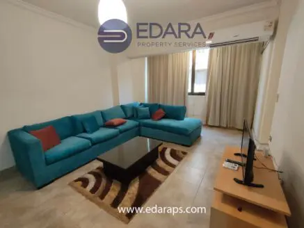 Living room featuring a blue sectional sofa, a coffee table, and a television on a stand.