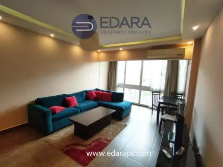 Modern living room featuring a teal sofa with red cushions and a wooden coffee table.
