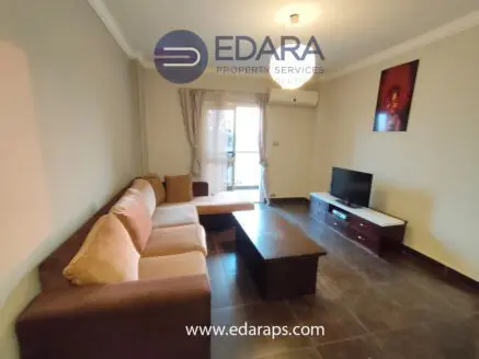 Living room featuring a brown sectional sofa, a coffee table, and a television unit against a neutral wall.