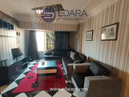 Living room featuring a black and white patterned floor, sofas, and a television unit.