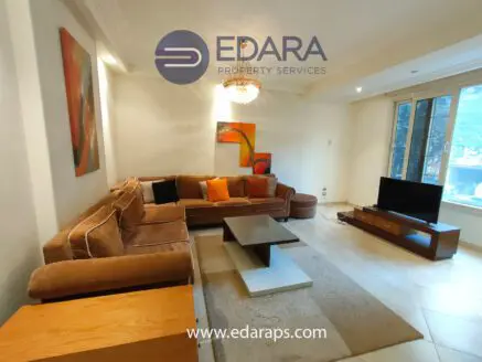 Living room featuring a large brown sectional sofa, a coffee table, and a television unit against a wall.