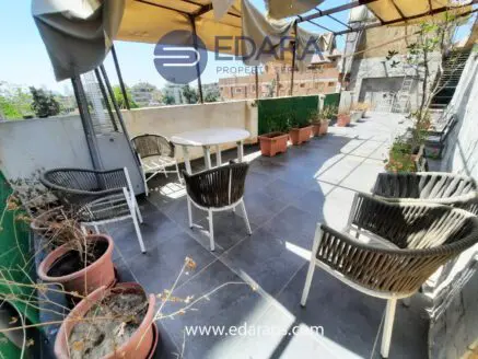 Outdoor seating area featuring a round table and several wicker chairs arranged on a tiled surface.