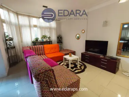 Living room featuring a colorful orange and patterned sofa, a television, and a coffee table.