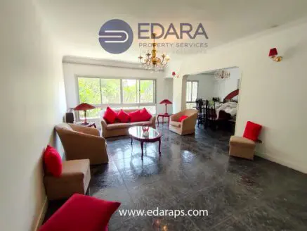 Living room featuring beige sofas with red accent cushions and a glass coffee table.