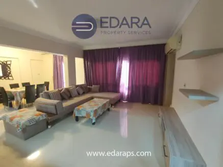 Spacious living room featuring a sectional sofa and dining area with curtains and light-colored walls.