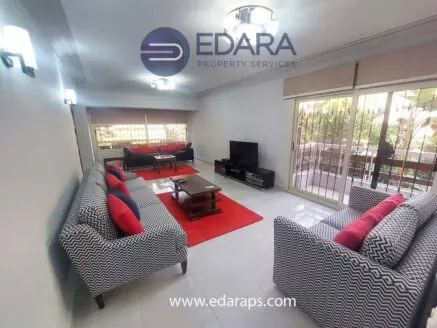 Modern living room featuring patterned sofas, a coffee table, and large windows with natural light.