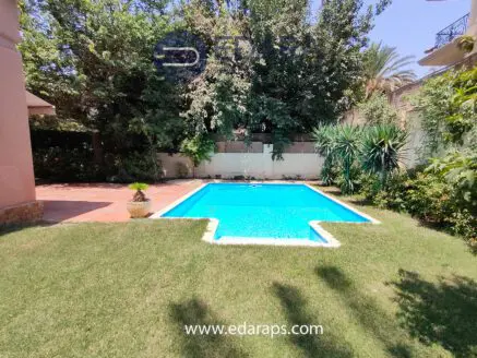 A clear swimming pool surrounded by grass and plants in a residential garden setting.