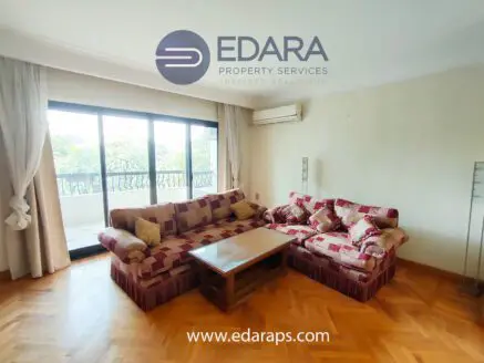 Living room featuring a large sofa set and a wooden coffee table in a bright space with large windows.