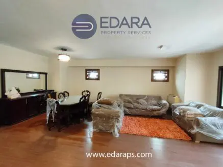 Living room featuring a dining table, chairs, and wrapped furniture in a neutral color scheme.
