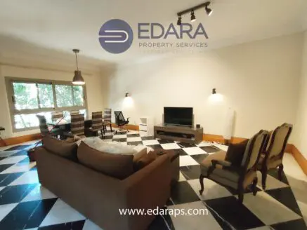 Modern living room featuring a sofa, chairs, and a television on a patterned floor.
