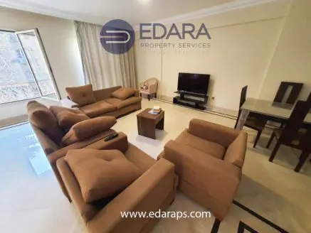 Living room featuring brown sofas, a television, and a dining table in a neutral color scheme.