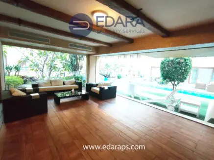 Indoor lounge area featuring a modern seating arrangement with a view of greenery and a pool.