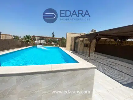 Swimming pool featuring clear blue water surrounded by a tiled deck and shaded areas.