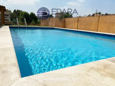 Swimming pool with clear blue water and a tiled edge, surrounded by a concrete deck.