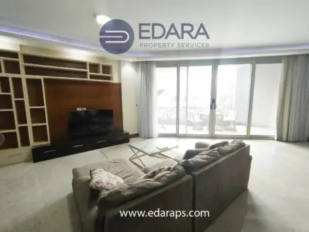 Contemporary living room with a television, seating area, and large windows allowing natural light.