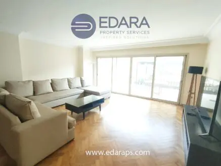 Modern living room featuring a large sectional sofa and a flat-screen television on a stand.
