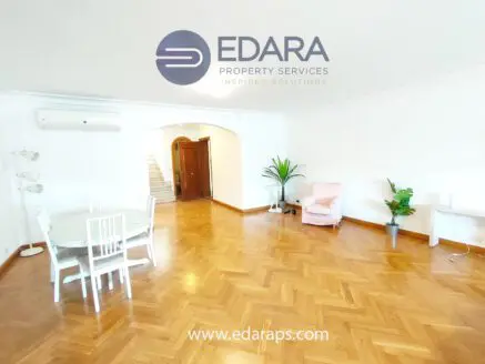 Bright interior living space featuring wooden flooring, a dining table, and a pink armchair.