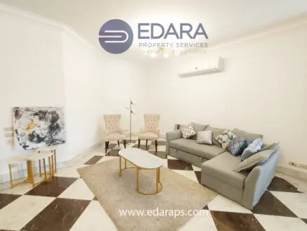 Modern living room featuring a gray sofa, two beige chairs, and a coffee table on a patterned floor.