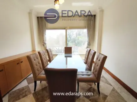 Dining room featuring a glass table surrounded by upholstered chairs with a view through large windows.