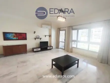 Spacious living room with a coffee table, TV unit, and decorative wall art in a neutral color scheme.