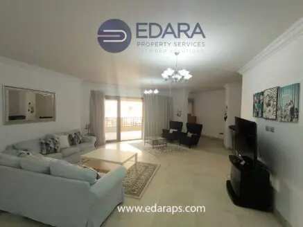 Spacious living room featuring a white sofa, television, and decorative wall art in a modern setting.