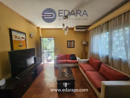 Living room featuring a red sofa, coffee table, and a television against a yellow wall.