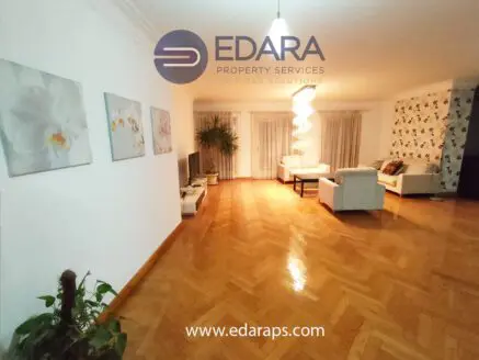 Living room featuring a sofa, decorative plants, and wall art in a modern setting.