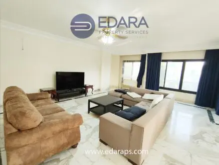 Living room featuring two sofas, a coffee table, and a television set against a light-colored wall.
