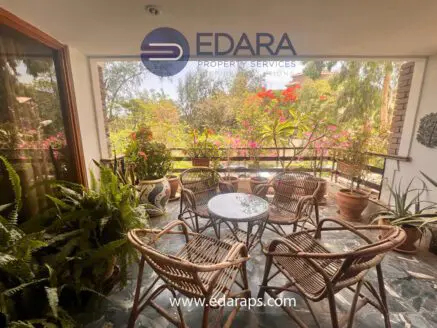 Seating arrangement with wicker chairs and potted plants in an outdoor space.