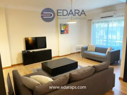 Modern living room featuring a gray sofa, television, and coffee table in a well-lit space.