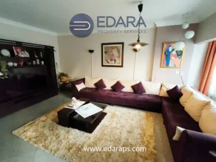Living room featuring a large purple sectional sofa, decorative pillows, and a coffee table on a plush rug.